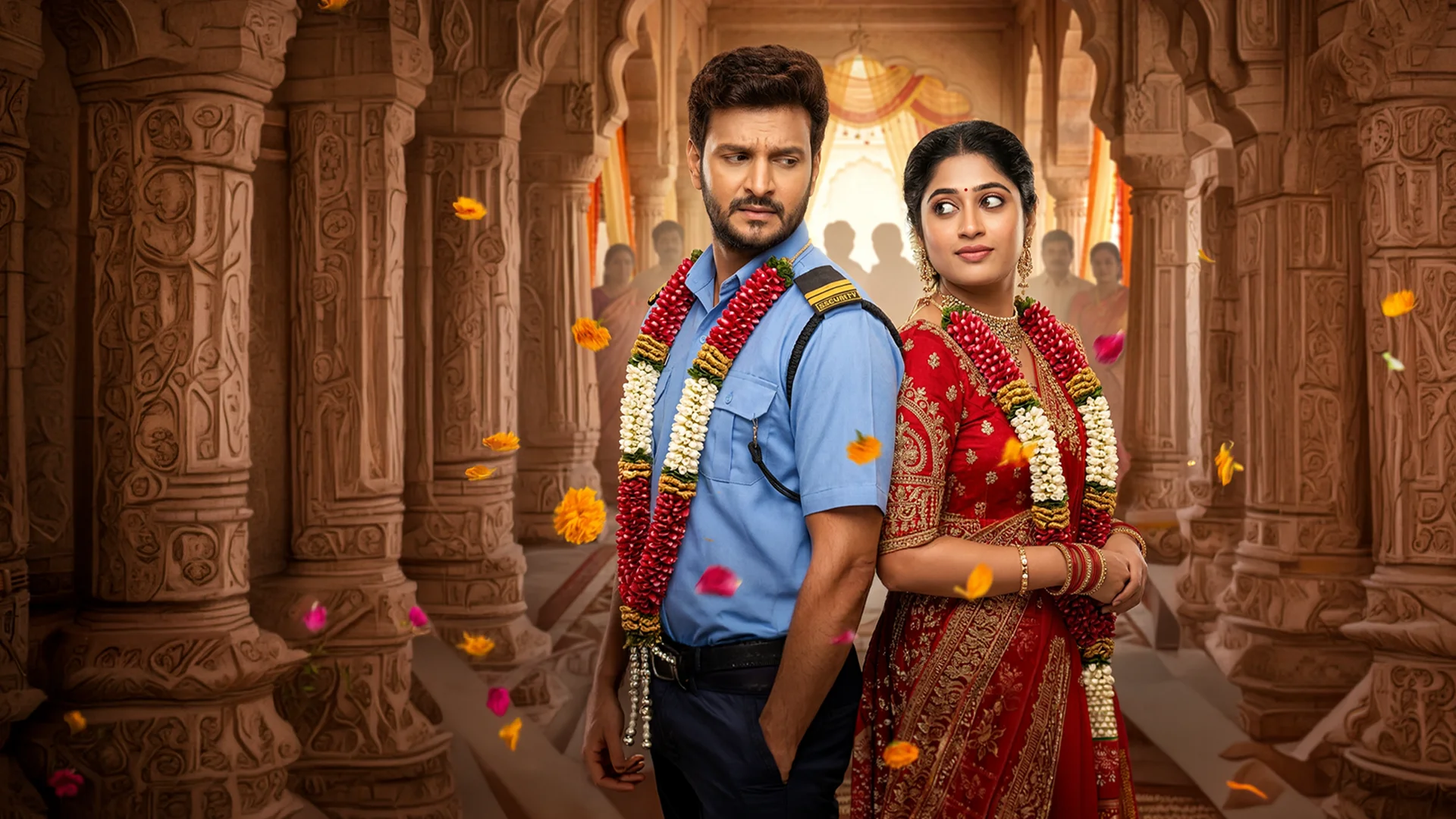 Bride and groom in traditional wedding attire stand back-to-back in a carved temple setting, garlands around their necks as petals fall around them.